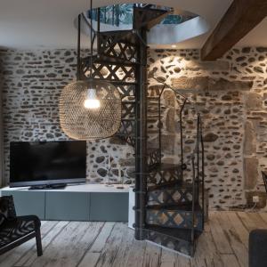 a spiral staircase in a living room with a tv at Maison dans le centre historique pour 6 personnes avec terrasse et parking in Pau