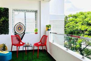 a balcony with red chairs and a table and a window at BluO 1BHK Gachibowli - Terrace Garden, Lift in Hyderabad