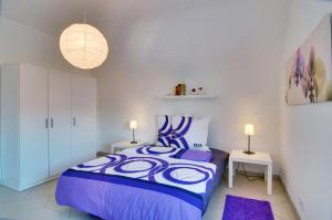 1 dormitorio con 1 cama de color púrpura y 2 lámparas en Ferienwohnung Hornisgrindeblick, en Obersasbach