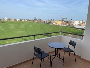 balcón con mesa, 2 sillas y un campo en Stunning 1-Bed Apartment in Larnaca near the sea, en Perivolia