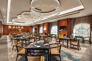 a restaurant with tables and chairs and a chandelier at Kunming Huiyue Wyndham Hotel in Kunming
