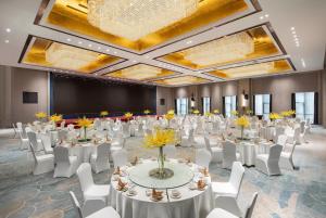 a banquet hall with white tables and chairs and a projection screen at Kunming Huiyue Wyndham Hotel in Kunming