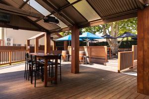 a wooden deck with tables and chairs and umbrellas at Family Hotel in Bathurst