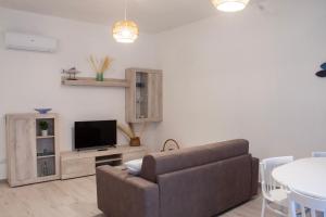 - un salon avec un canapé, une télévision et une table dans l'établissement Blu Mare Apartment, à Alghero