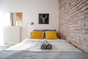 łóżko z żółtymi poduszkami i ceglaną ścianą w obiekcie LION apartments - Gold w Krakowie