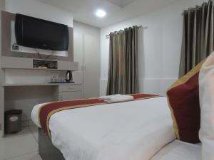 a hotel room with a bed and a flat screen tv at Hotel Reegate Inn in Cochin