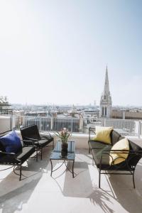 einen Balkon mit Sofas und Blick auf ein Gebäude in der Unterkunft Hôtel De Sers Champs Elysées Paris in Paris