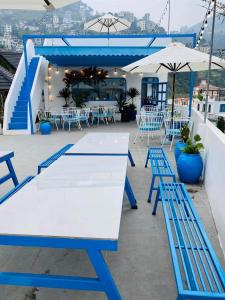 Cau May Tam Dao - Venuestay في تام داو: طاولة بيضاء وكراسي زرقاء وطاولات على الفناء