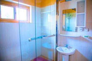 a bathroom with a glass shower and a sink at Iris Guest House in Kigali