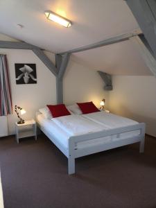 a bedroom with a white bed with red pillows at Kleene Helene in Wulfen auf Fehmarn