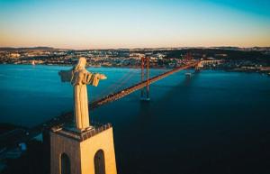 uma estátua de um Cristo o redentor em frente a uma ponte em River View & Close to the Beach - Quarto em Almada em Almada