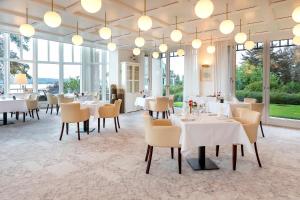 un restaurante con mesas y sillas blancas y ventanas en LILIENBERG, en Ermatingen