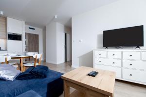 uma sala de estar com uma cama, uma televisão e uma mesa em Resort Apartamenty Klifowa Rewal 83 em Rewal