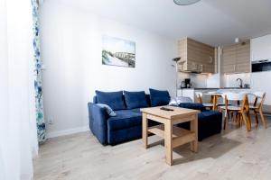 uma sala de estar com um sofá azul e uma mesa em Resort Apartamenty Klifowa Rewal 83 em Rewal
