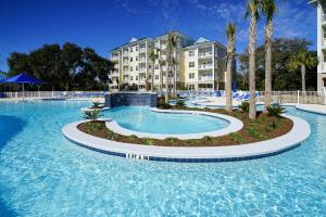 a pool at a resort with palm trees and a building at Bluewater by Spinnaker Resorts in Hilton Head Island