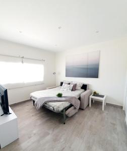 a white bedroom with a bed and a tv at Playa Doñana 2 in Sanlúcar de Barrameda