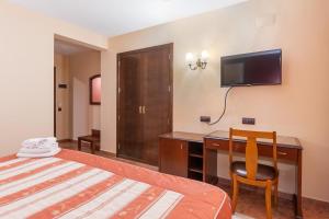 Habitación de hotel con cama, escritorio y TV. en Hotel Puerta de Javalambre, en La Puebla de Valverde