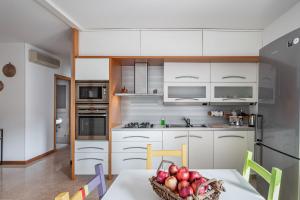 een keuken met witte kasten en een tafel met een fruitschaal bij Padova Palestro Pastel Apartment in Padua