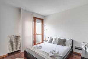 een witte slaapkamer met een bed en een raam bij Padova Palestro Pastel Apartment in Padua