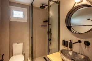een badkamer met een wastafel, een spiegel en een toilet bij Calypso beach front apartment in Hanioti