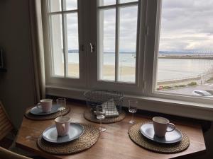 a table with two plates and glasses and a window at L améthystes in Crozon