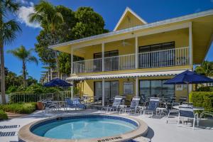 un edificio con piscina, sillas y sombrillas en Charter Club Resort Of Naples Bay, en Naples