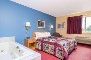 a hotel room with a bed and a bath tub at Days Inn by Wyndham West-Eau Claire in Eau Claire