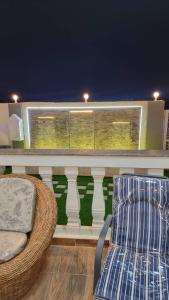 una silla y una silla en un balcón por la noche en Smart Chalet:سمارت شالية en Salalah
