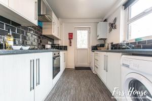 a kitchen with white cabinets and a washer and dryer at Firs Serviced Accommodation in Leigh