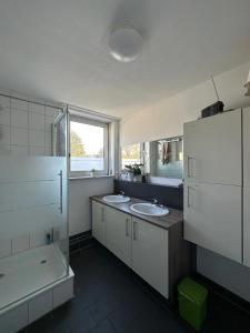 een badkamer met 2 wastafels, een bad en een raam bij WinWin im Westen in Bielefeld