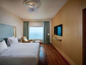 a hotel room with a bed and a television at Novotel Visakhapatnam Varun Beach in Visakhapatnam