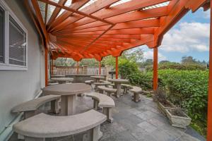 eine Terrasse mit Tischen und Stühlen unter einer orangefarbenen Pergola in der Unterkunft Best Western Plus Northwoods Inn in Crescent City