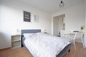 a white bedroom with a bed and a desk at Air Apartments 10 in Bremen