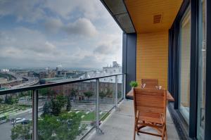 a balcony with a wooden chair and a view of a city at Les Immeubles Charlevoix - Le 760-431 in Quebec City