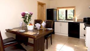 a kitchen with a wooden table with flowers on it at Fern Wood Estate in Glengarriff