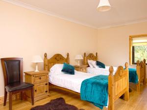 a bedroom with two beds and a chair at Fern Wood Estate in Glengarriff