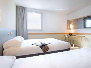 um quarto de hotel com duas camas e uma secretária em Ibis Budget Fréjus St Raphaël centre et plages à 900m em Fréjus