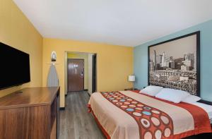 ein Hotelzimmer mit einem Bett und einem Flachbild-TV in der Unterkunft Super 8 by Wyndham Eddyville/Kuttawa in Eddyville
