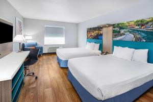a hotel room with two beds and a desk at Days Inn & Suites by Wyndham San Antonio near Frost Bank Center in San Antonio