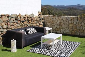 a couch and a table on the grass with a stone wall at CASA MARGARITA in El Castillo de las Guardas