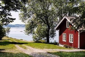 a red house on the shore of a lake at Herregården Hoel - De Historiske in Nes i Ådal
