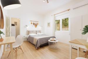 a white bedroom with a bed and a table at Aloe Apartments in Corfu
