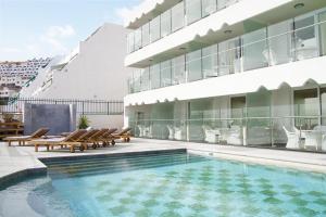 een zwembad met stoelen en een gebouw bij Villa Magna in Puerto Rico de Gran Canaria