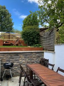 einen Holztisch und Stühle auf einer Terrasse mit Grill in der Unterkunft Muller residence in Bristol