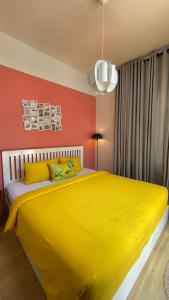 a yellow bed in a room with a red wall at Roemah Renjana Rosie Makassar in Makassar