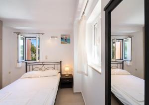 two beds in a room with two windows at Boursinos cozy apartments by Imagine Lefkada in Lefkada