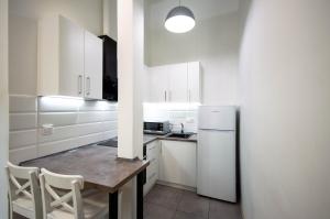 a white kitchen with a table and a refrigerator at Kyiv White Apartment in Kyiv