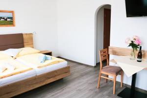 um quarto com uma cama e uma mesa com uma cadeira em Weingut & Gästehaus Dombi Weiss em Podersdorf am See