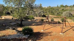 a swing set in a field with a tree at Hakuna matata in Benagil