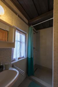 a bathroom with a green shower curtain and a sink at Csavargó Tanya in Szalafő